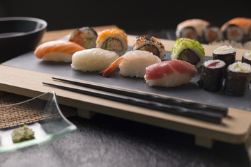 Sushi Set sashimi and sushi rolls served on stone slate