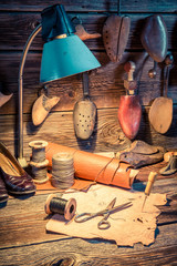 Shoes, tools and leather in old cobbler workshop