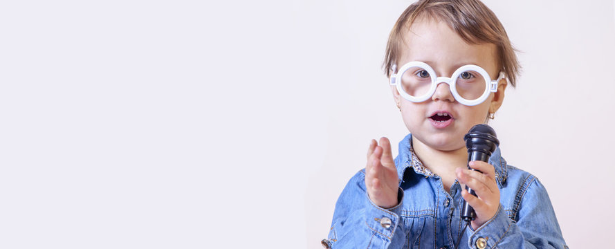 The famous actress. Humorous photo of cute child girl singing with a microphone (Happy childhood, teaching singing, music, child development concept)
