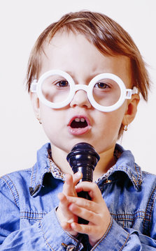 The famous actress. Humorous photocute child girl singing with a microphone (Happy childhood, teaching singing, music, child development concept)
