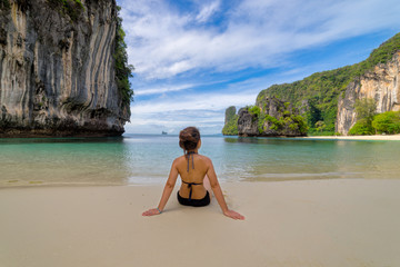 Young women wearing bikini relaxing sitting in topical beach on Koh Hong islands in Andaman sea at...