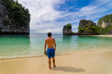 Young man traveler relaxing lying down in tropical beach on Koh Hong islands in Andaman sea at Krabi near Phuket southern of Thailand