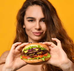 Woman eat burger sandwich with hungry mouth on yellow background