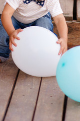 baby boy playing in isolated white studio, with colorful balloons for his birthday