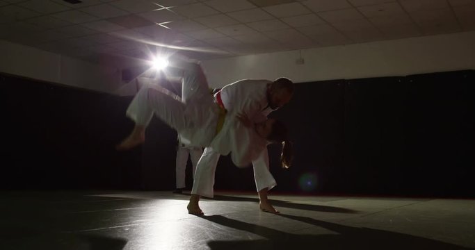 Two young martial arts athletes practice while a trainer assesses their moves.