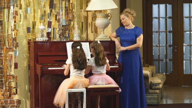 mother and daughters learn to play piano together in home