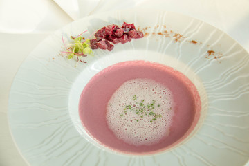 white bowl filled with beetroot soup garnished with sour cream