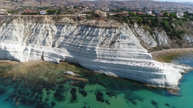 Aerial bird view flight towards Stair of the Turks in Italian Scala dei Turchi rocky cliff on coast of Realmonte near Porto Empedocle southern Sicily Italy it has become popular tourist attraction 4k