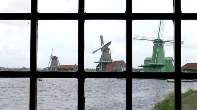 windmills as seen through a window at zaanse schans near amsterdam, netherlands