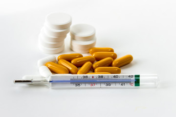 Thermometer showing high body temperature and pills for healing fever, cold on white background.