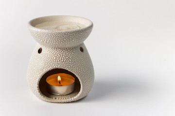 Aroma lamp with burning candle and water with drop of aroma oil on white background with blank...