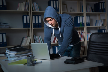 Young hacker hacking into computer at night