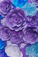 blue, purple and white paper flowers on a lilac wall. Photo Area