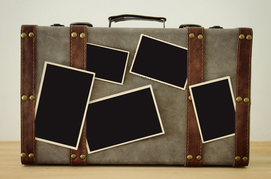 Image of old vintage luggage with blank photos for photography montage mockup over wooden floor.