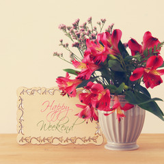 summer bouquet of red flowers in the vase over wooden table and white background.