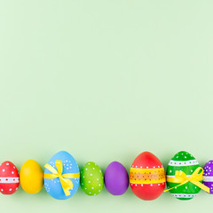 Colorful easter eggs on pastel green background flat lay. Copy space