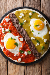 huevos divorciados, fried eggs on corn tortillas with two salsas, mexican breakfast. Vertical top view