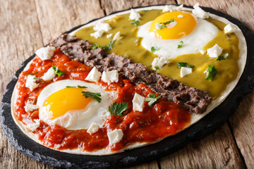Mexican breakfast huevos divorciados of eggs with Frijoles refritos, sauces roja and verde and cheese Queso Fresco on a corn tortilla. Horzontal