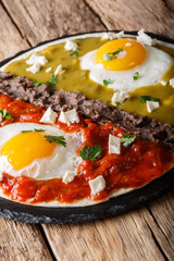 Mexican eggs huevos divorciados with Frijoles refritos, salsa roja and verde and cheese Queso Fresco close-up. Vertical