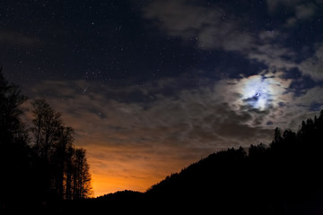 Fototapeta na wymiar Night sky full of stars with waxing crescent of moon and sunset under them