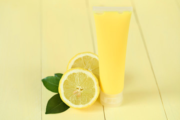 Cosmetics with lemon extract. yellow shower gel, body cream with lemon extract and fresh lemon in a cut on a yellow wooden plank background.Organic Natural Cosmetics