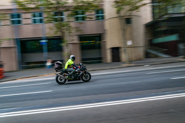 A motorcycle moving on the road, Sydney, Australia. A motorcycle in motion on the road, blurred building in background.