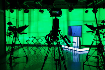Silhouette of a digital video camera in front of a green screen.