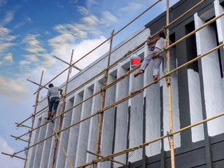 Painted workers are painting a  building with on bamboo scaffolding.climb up for paint outside...