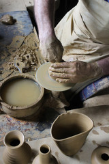 A raw clay pot in the hands of a Potter. Pottery art work:Hands make the mold with spirituality. Craftsman artist making craft, pottery, sculptor from fresh wet clay on pottery wheel, selected focus