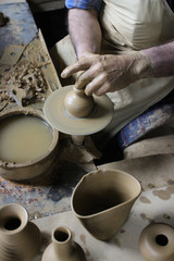 Fototapeta na wymiar A raw clay pot in the hands of a Potter. Pottery art work:Hands make the mold with spirituality. Craftsman artist making craft, pottery, sculptor from fresh wet clay on pottery wheel, selected focus