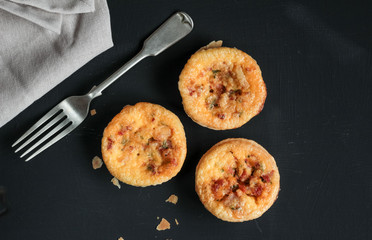  Mini savory quiches on black table with fork - Top view photograph