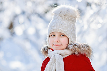Girl in red coat, knit ivory scarf and hat looking at camera