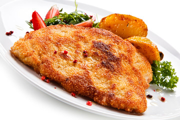 Fried pork chop, baked potatoes and vegetable salad