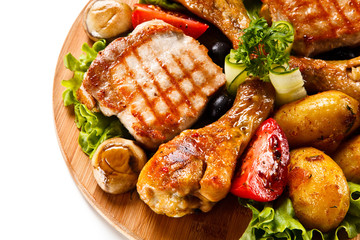 Grilled steak and drumsticks with potatoes on cutting board