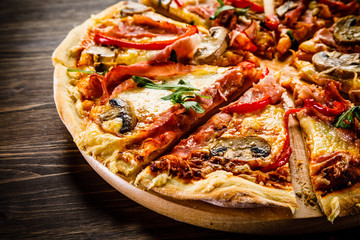 Pizza with ham and vegetables on wooden table