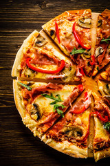 Pizza with ham and vegetables on wooden table