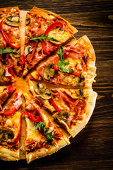 Pizza with ham and vegetables on wooden table