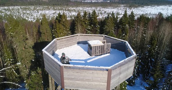 Man and a kid on a watchtower Cinema 4k aerial view of a male and a boy enjoying the view on a observation tower, on a cold sunny day, in Torronsuo national park, Kanta-hame, Finland