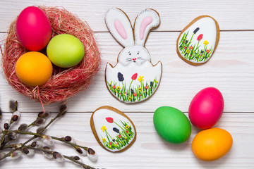 Gingerbread Easter set painted eggs and willow twig on white wooden background.  Easter Bunny and eggs, gingerbread