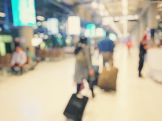 Abstract blurred image background of group people or arriving passengers with their suitcases holding luggage walking in international  airport terminal, travelling or business concept. vintage tone.