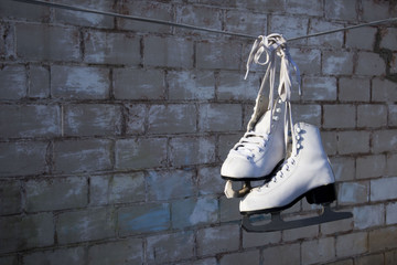 white skates hanging on a rope against a brick wall