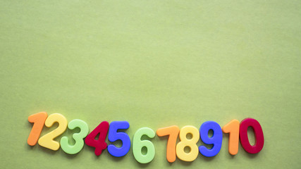 children's multi-colored numbers on a green background, copy space