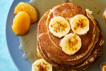 Pile of homemade pancakes with honey and walnuts on rustic wooden background, selective focus