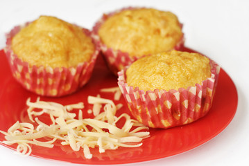 Homemade cheese muffins and shavings of cheese on a red plate. Close-up.