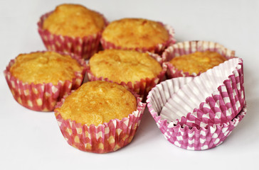 Homemade muffins and paper colored cake pans on white. Close-up