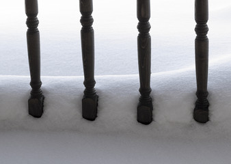The wooden balusters of the terrace are covered with fresh snow.