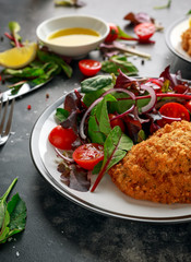 Breaded Chicken Kiev breast stuffed with butter, garlic and herbs served with vegetables in a plate.