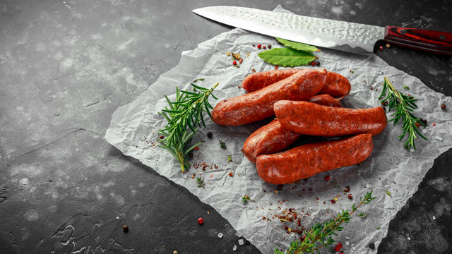 Freshly made raw breed butchers sausages in skins with herbs on crumpled paper.