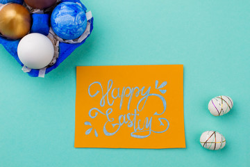 Easter card and painted eggs, top view. Easter greeting card and styrofoam eggs on turquoise background. Festive Easter mood.