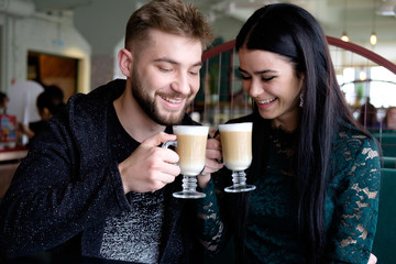 white young couple drinking cappuccino in the cafe and smiling